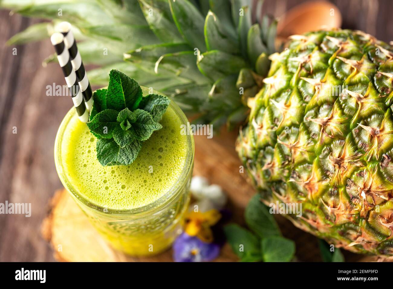 Limette Smoothie mit grünen Blättern in Kombination mit Ananas im Hintergrund verziert, schmackhaftes Konzept Stockfoto