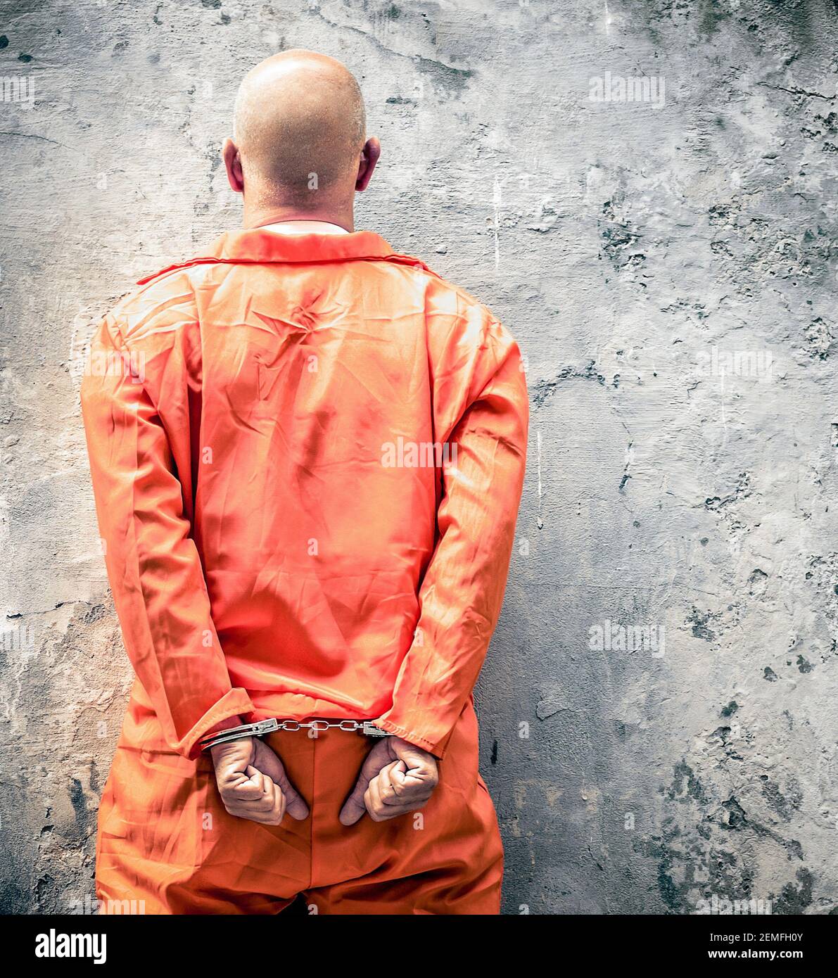 Gefangene in Handschellen, die an der Gefängnismauer auf die Todesstrafe warten Stockfoto