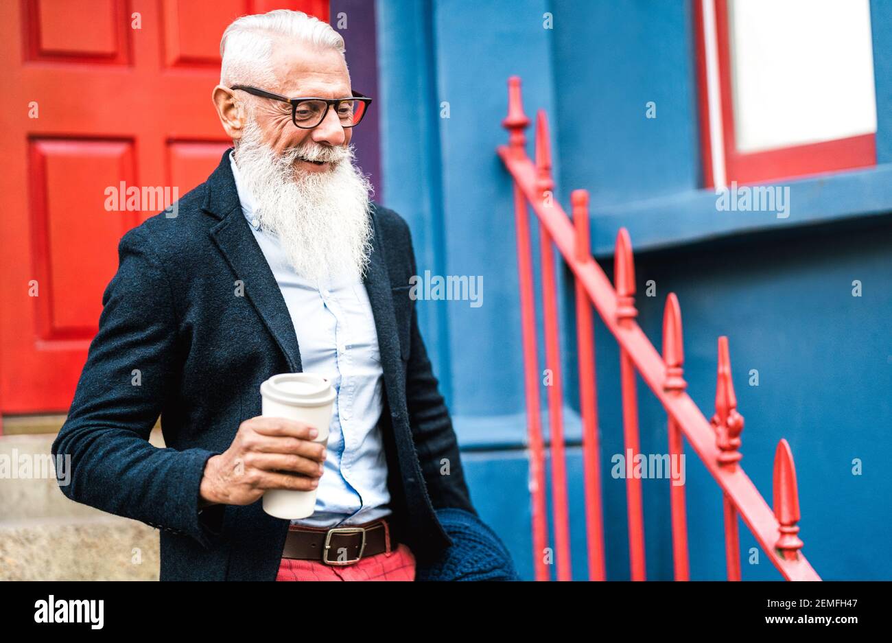 Hipster-Geschäftsmann, der mit einer Tasse Kaffee zum Mitnehmen unterwegs ist Hintergrund - trendige alte Person tragen lässige Mode Kleidung - Glücklicher älterer Lebensstil Stockfoto