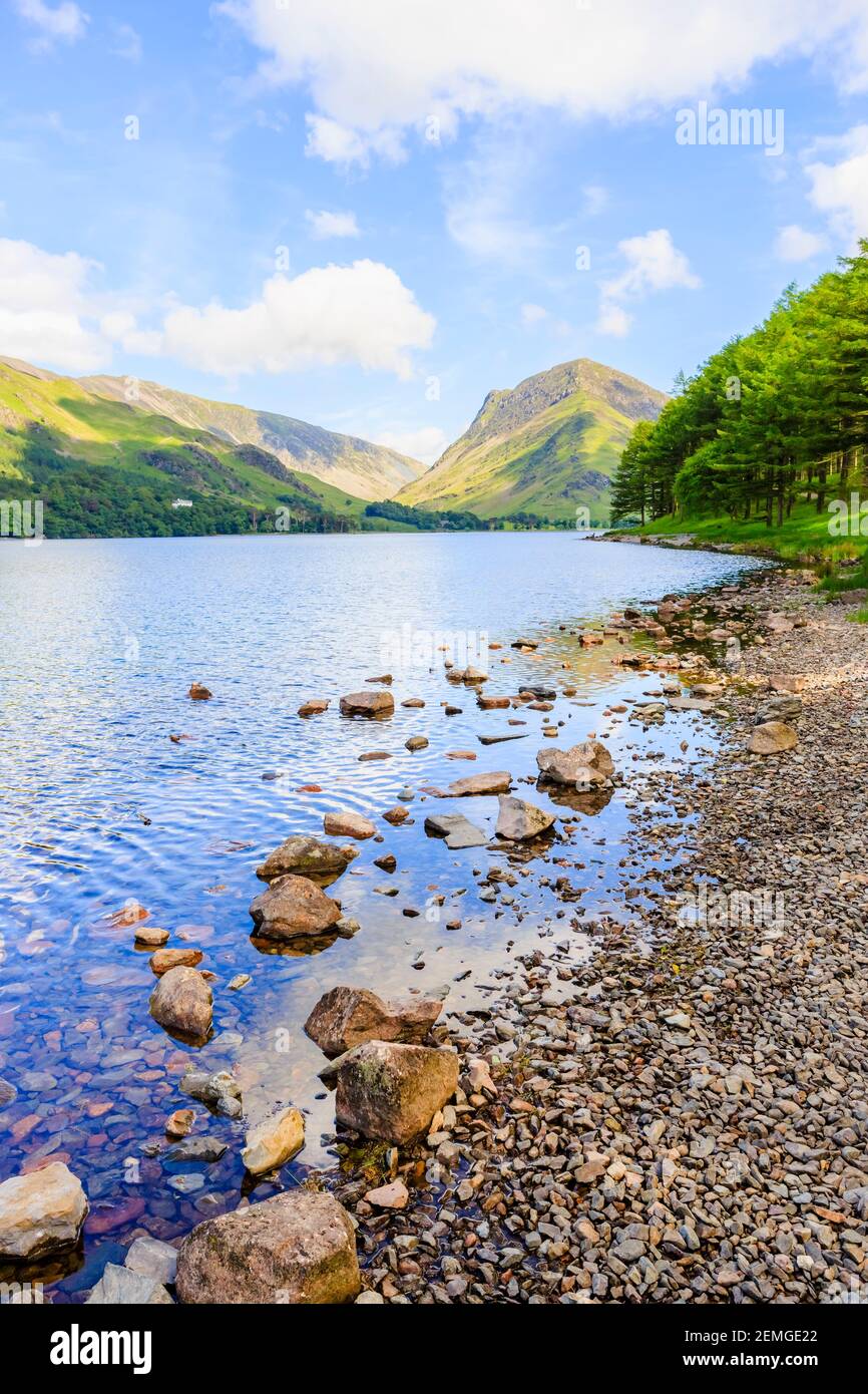 Blick über den Buttermere See entlang der felsigen Küste Richtung Fleetwith Hecht an einem sonnigen Sommertag Stockfoto