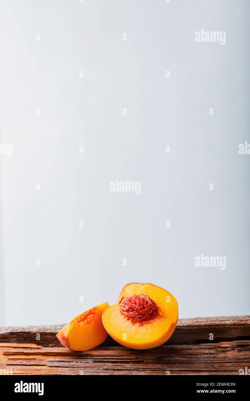 Pfirsiche mit Blättern auf Holzbrett. Pfirsich in Hälften mit Knochen. Reife saftige Pfirsiche. Frische Bio Pfirsiche Obst auf weißem Hintergrund. Rustikal, minimalistisch Stockfoto