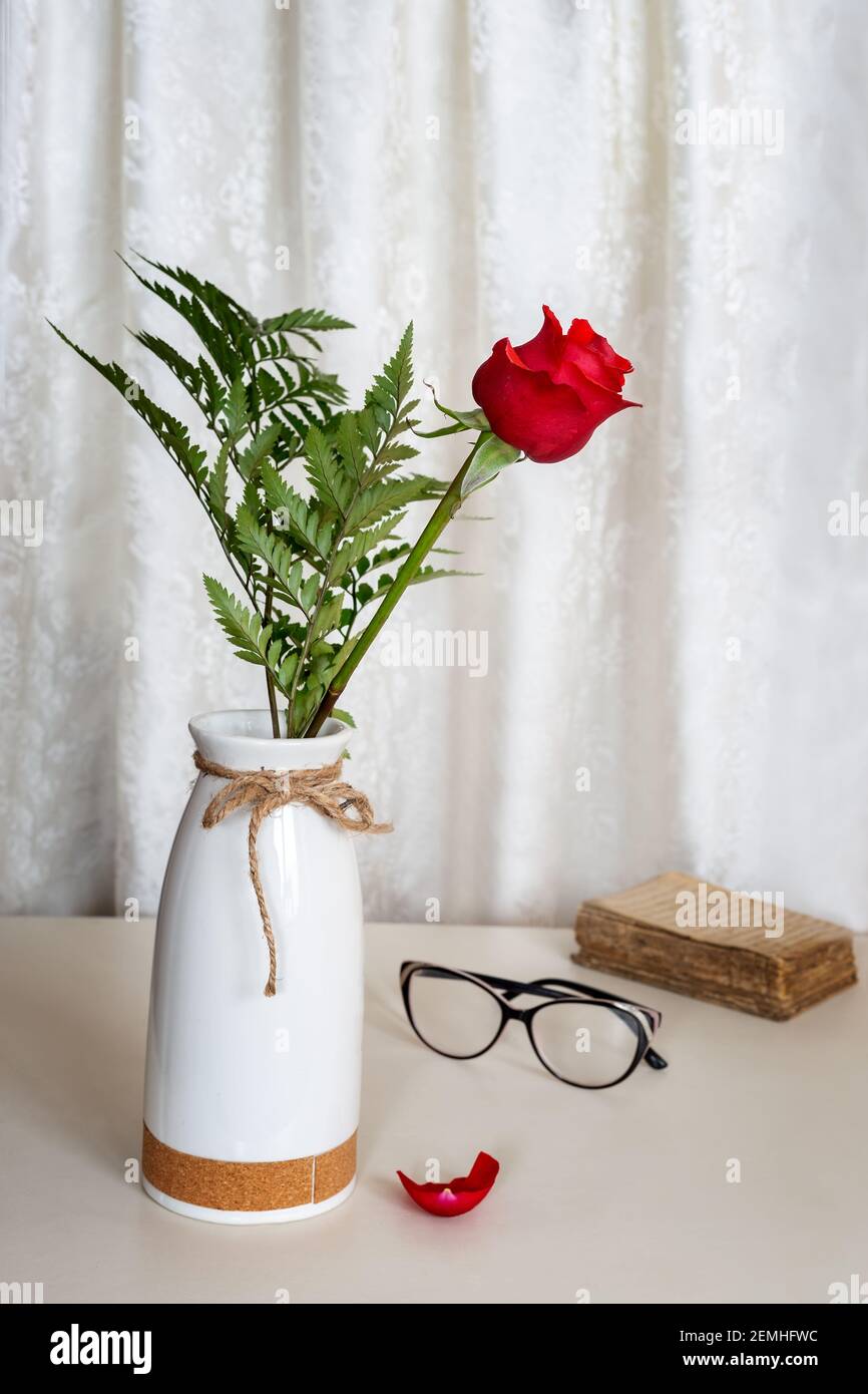 Rote Rose auf dem Tisch in einer Keramikvase Stockfoto