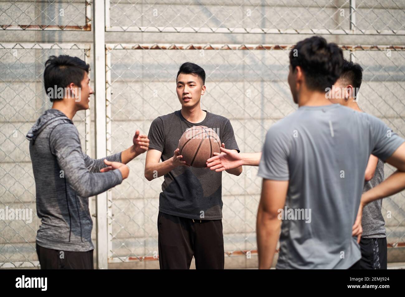 Junge asiatische Basketballspieler unterhalten sich entspannt auf dem Platz im Freien Stockfoto