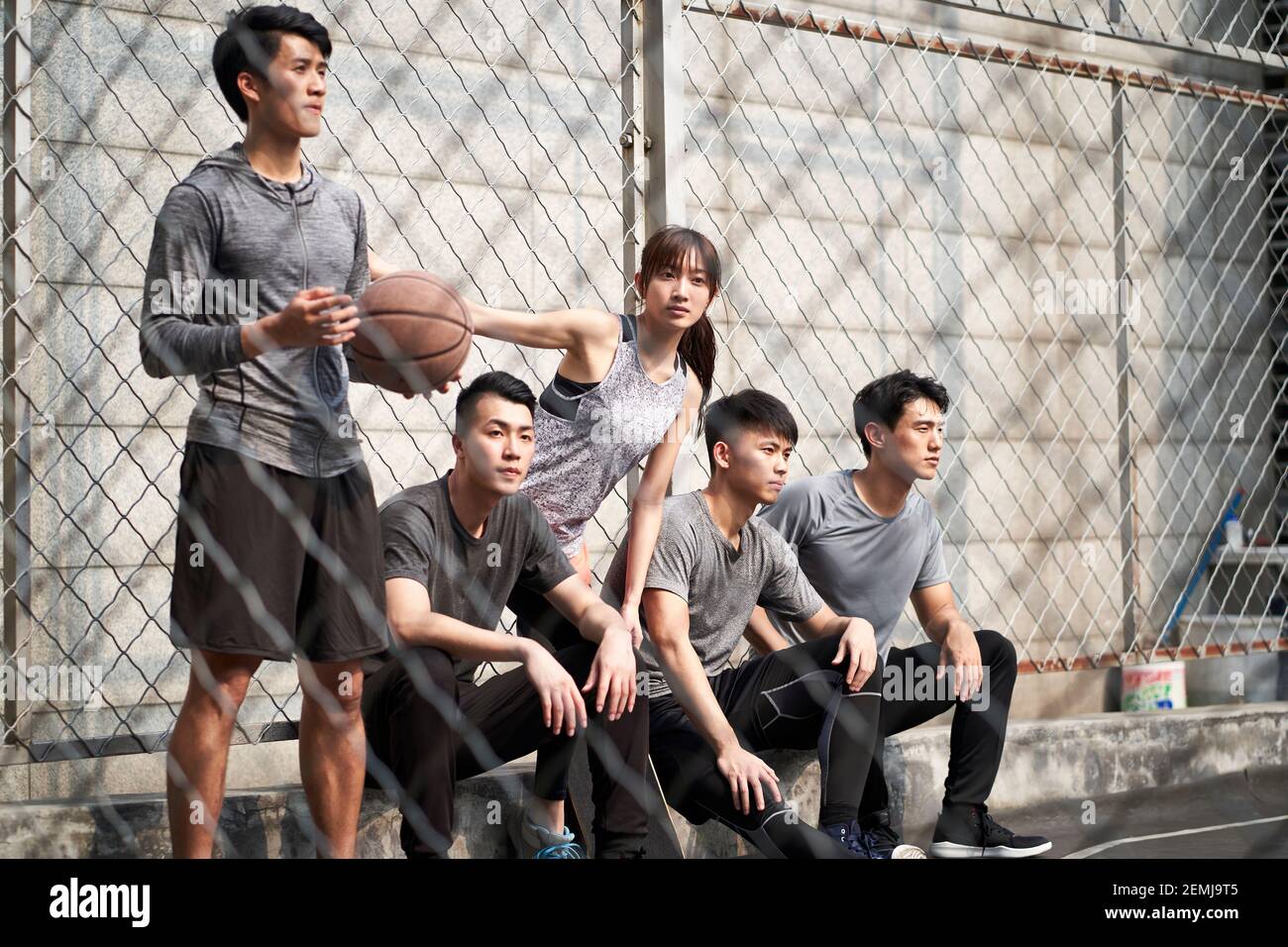 Gruppe von fünf asiatischen jungen Erwachsenen Männer und Frau, die sich auf dem Basketballplatz im Freien entspannen Stockfoto