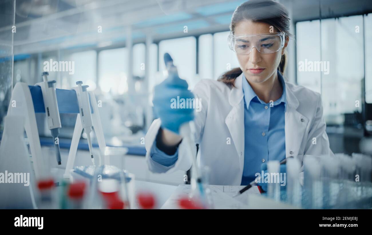 Medical Research Laboratory: Portrait einer schönen Wissenschaftlerin in Goggles mit Mikropipette für die Testanalyse. Advanced Scientific Lab für Stockfoto