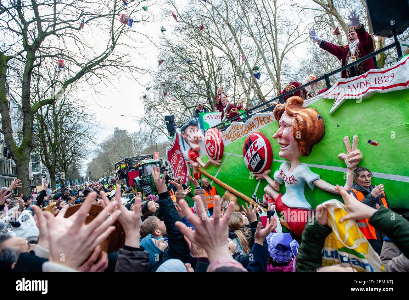 Menschen in Kostümen werden gesehen, wie sie während der Parade Süßigkeiten in die Menge werfen. In Düsseldorf stehen nicht weniger als 300 Karnevalsveranstaltungen, Bälle, Jubiläen, Empfänge und Kostümpartys auf dem Kalender der Karnevalsveranstaltungen. Das Motto dieser Saison ist ‘gemeinsam Jeck’. Die Feierlichkeiten kulminieren in der Rosenmontagsparade. Mehr als 30 Musikensembles und 5.000 Teilnehmer nehmen an der Prozession durch die Stadt Teil. Aufwendig gebaute und dekorierte Wagen adressieren kulturelle und politische Themen und können satirisch, urkomisch und sogar kontrovers sein. Die politisch thematisierten Schwimmer von satir Stockfoto