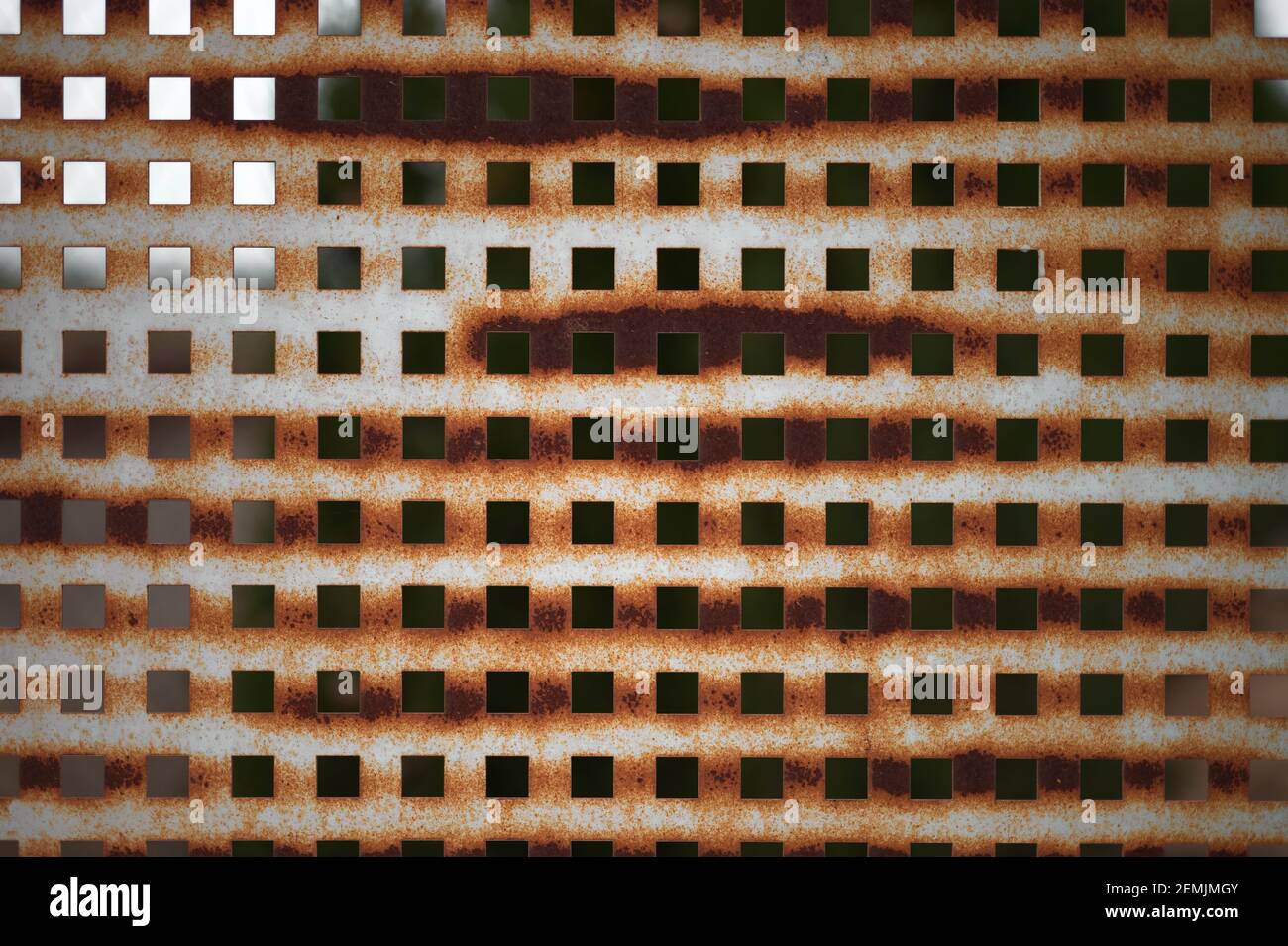 Detail eines verrosteten Blechzauns mit quadratischen Löchern Stockfoto