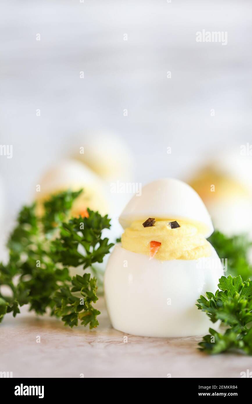Deviled Eier für Ostern geschmückt als niedliche kleine Küken schlüpfen aus Eiern mit Karottenschnabel und Algen Augen. Extrem geringe Schärfentiefe mit Unschärfe Stockfoto