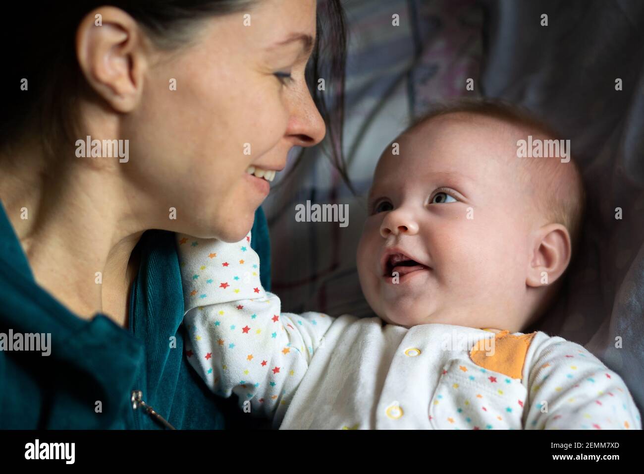 Crop Frau toothy lächelnd, während Blick auf entzückende Baby im Schlafzimmer zu Hause. Stockfoto