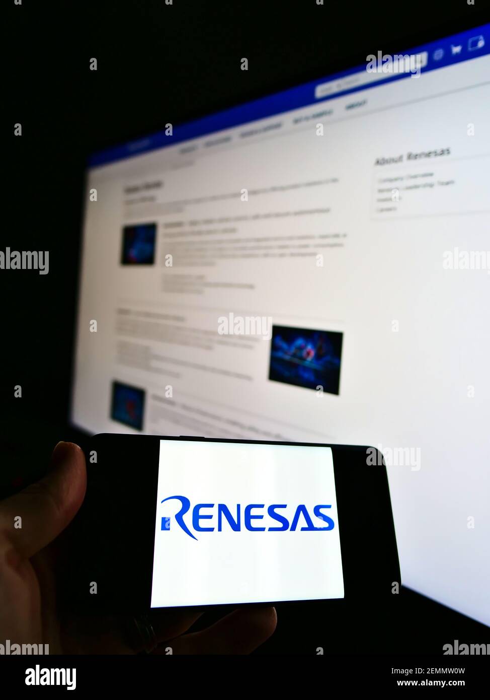 Person, die Mobiltelefon mit Logo der japanischen Firma Renesas Electronics Corporation auf dem Bildschirm vor der Webseite hält. Konzentrieren Sie sich auf die Anzeige von Mobiltelefonen. Stockfoto
