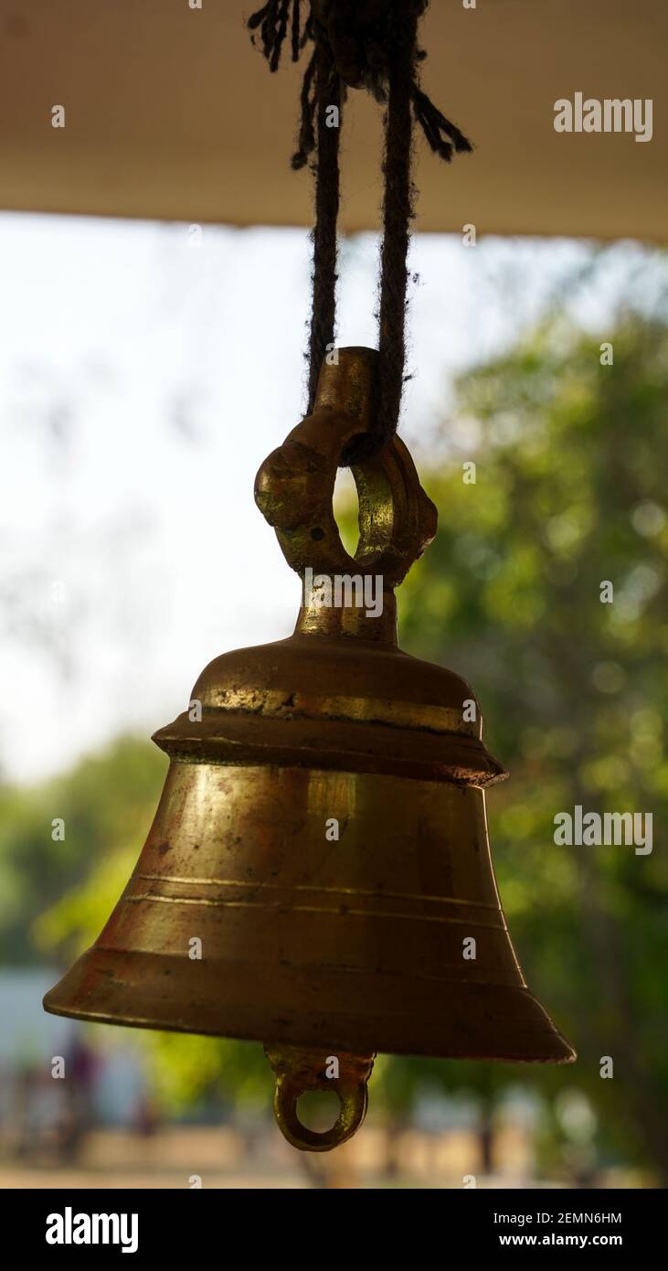 Bronze Glocke in indischen Tempel in den grünen Kulturen verwischen Hintergrund. Hinduistischer Tempel Messing Glocke in Gold hängen Stockfoto