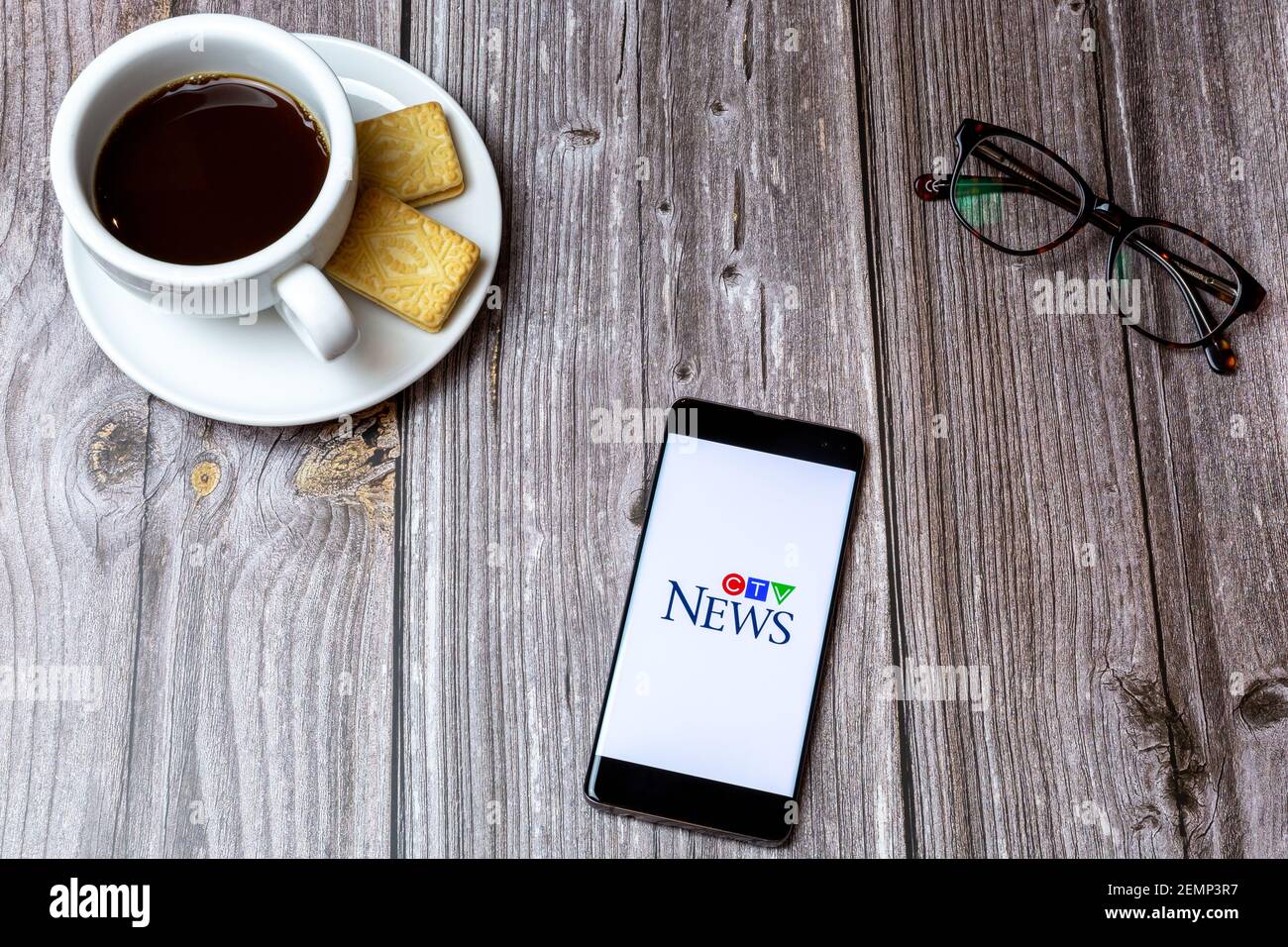 Ein Handy oder Handy auf einem Holztisch Mit der CTV News App neben einem Kaffee öffnen Und Brille Stockfoto