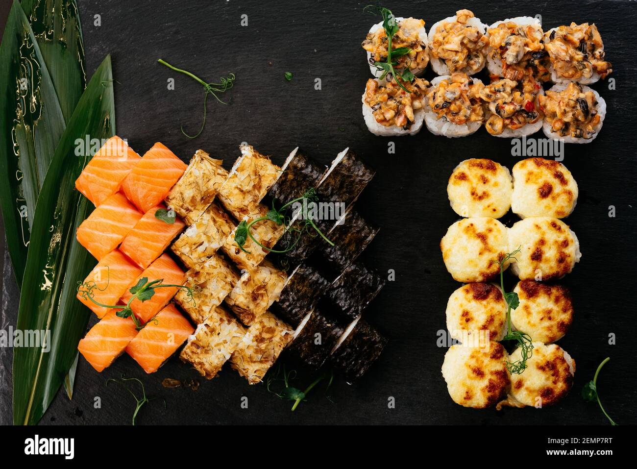 Sushi und Sojasauce in einer Schüssel und Holzstäbchen auf einem grauen Holztisch. Japanisches Essen. Sushi-Set. Verschiedene Brötchen. Menü. Stockfoto