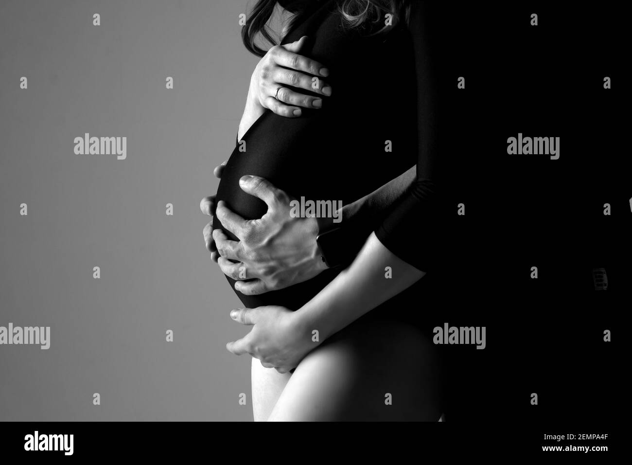 Ehemann und Ehefrau halten während der Schwangerschaft ihren Bauch fest Stockfoto