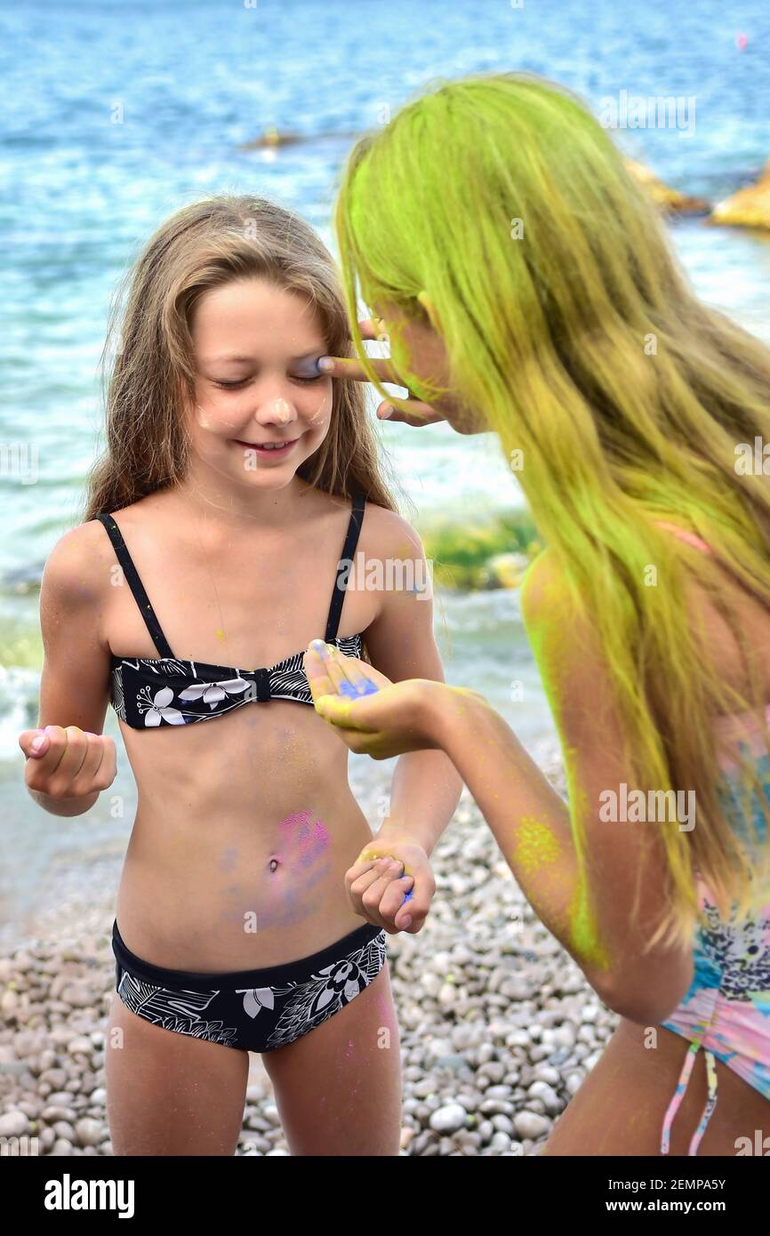 Zwei Mädchen am Strand malen sich gegenseitig mit hell Farben heilig Stockfoto