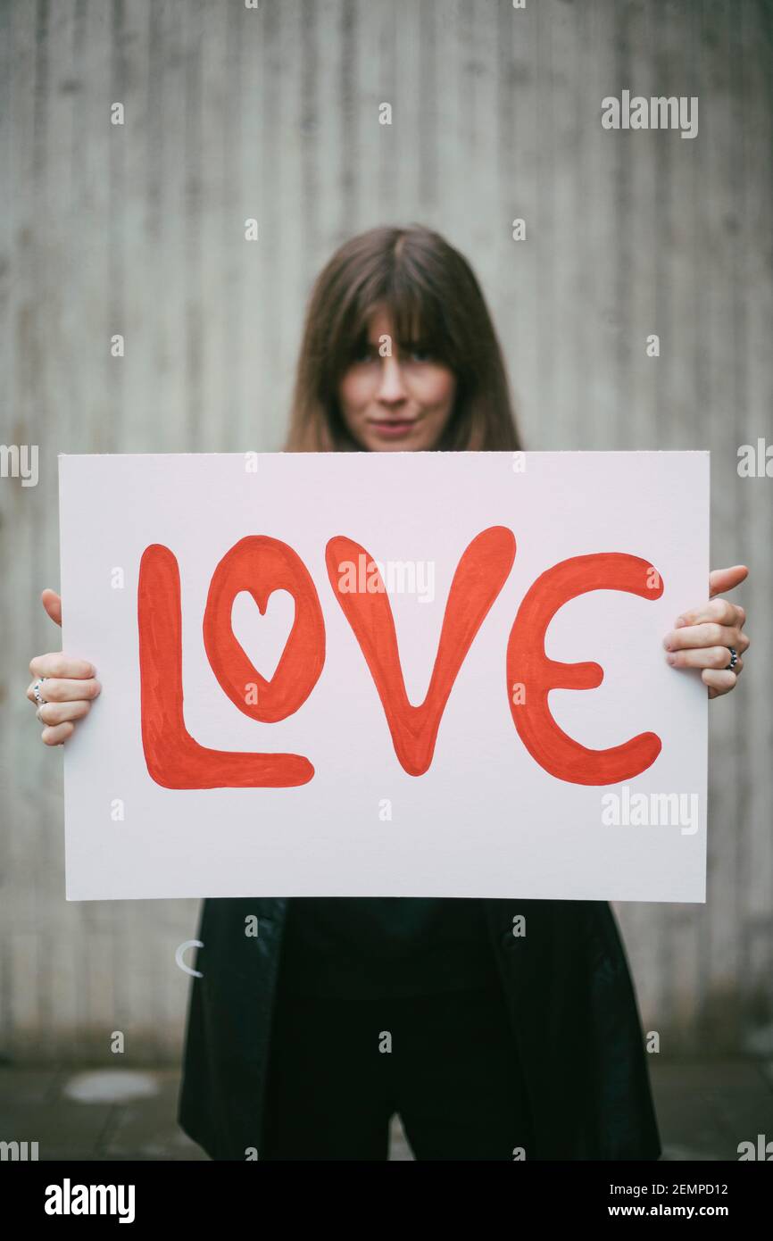 Aktivistin mit Liebesposter gegen Wand Stockfoto