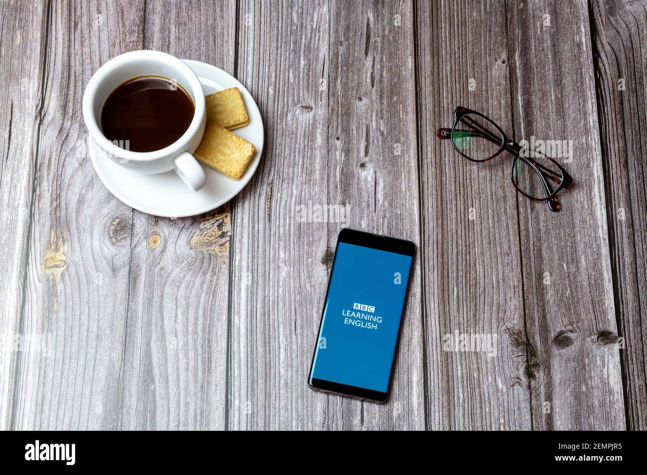 Ein Handy oder Handy auf einem Holztisch Mit der BBC Learning English App neben einem geöffnet Kaffee Stockfoto