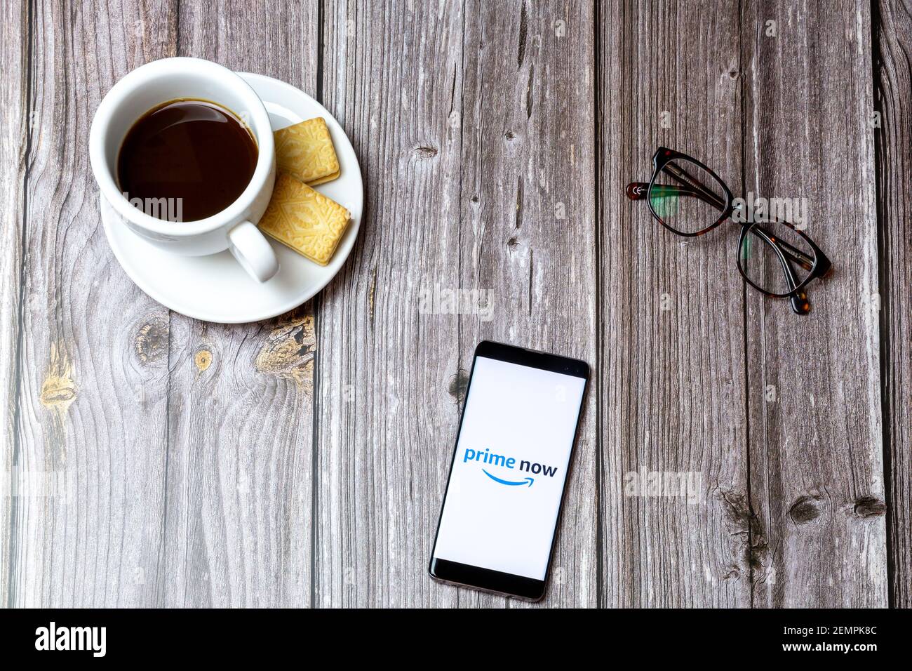 Ein Handy oder Handy auf einem Holztisch Mit der Amazon Prime Now App öffnen sich neben einem Kaffee und Gläser Stockfoto