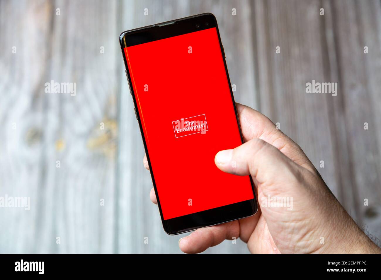 Ein Mobiltelefon oder Mobiltelefon, das von einem gehalten wird Hand mit der Economist App geöffnet auf dem Bildschirm Stockfoto