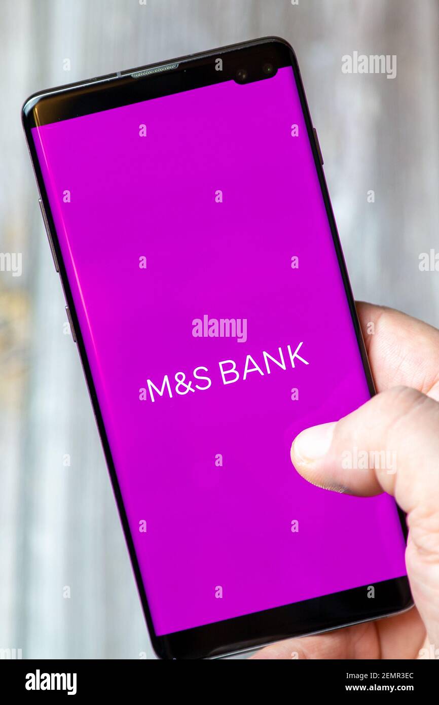 Ein Mobiltelefon oder Mobiltelefon, das von einem gehalten wird Hand mit der M&S Bank App geöffnet auf dem Bildschirm Stockfoto