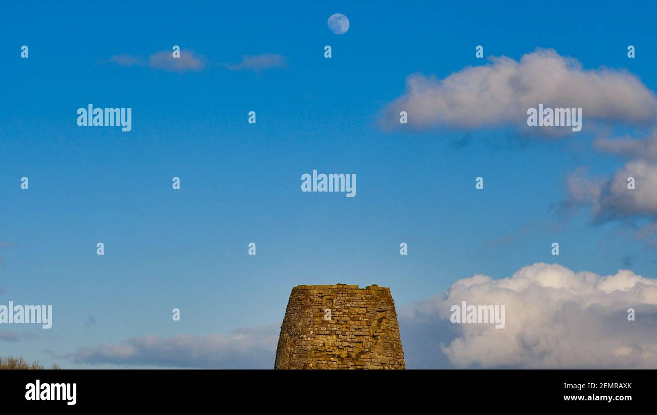 Vollschneemond steigt über einer alten stillvollen Windmühle Carsington Weide, Hopton, nahe Wirksworth, Derbyshire, England, VEREINIGTES KÖNIGREICH Stockfoto