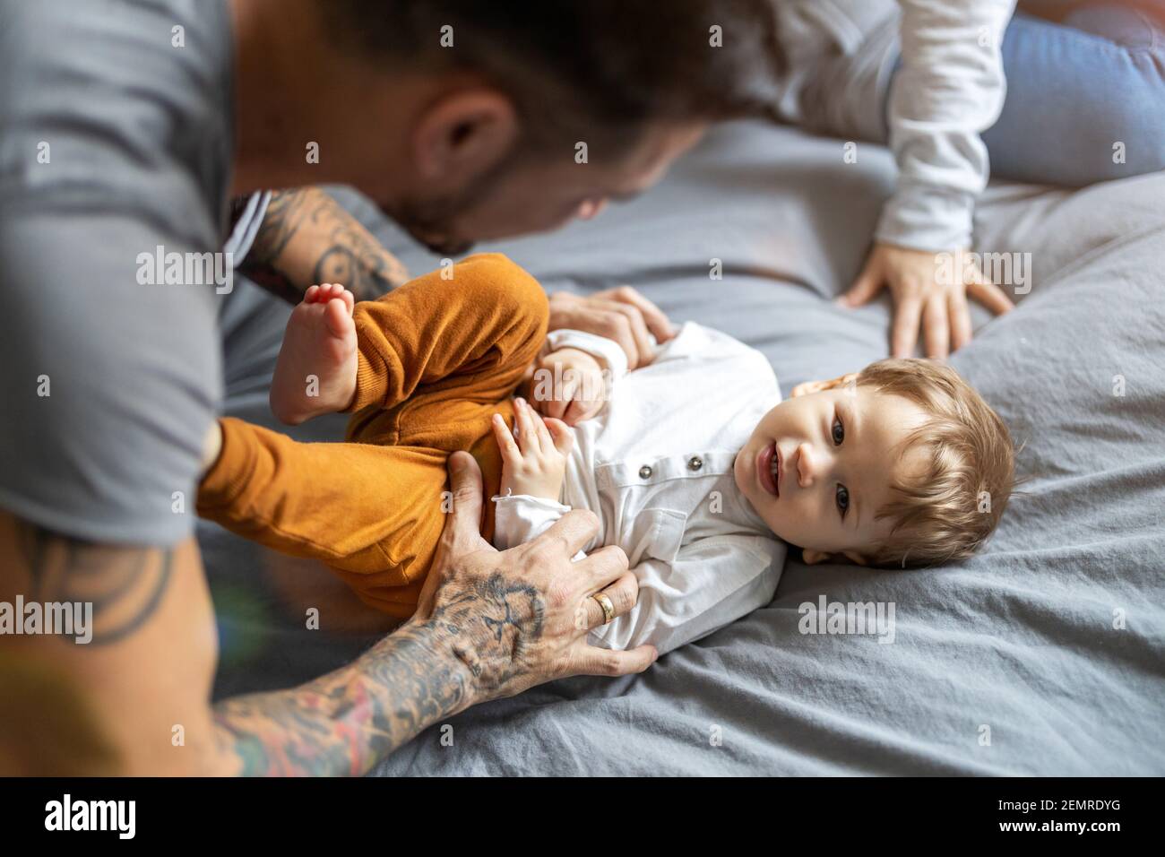 Vater kitzelt seinen kleinen Sohn im Bett Stockfoto
