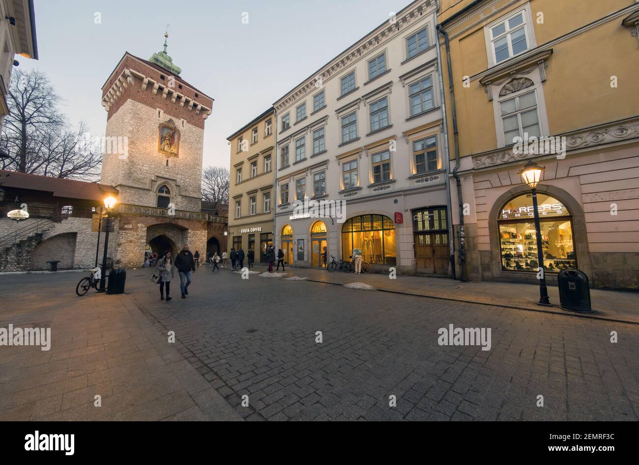 Krakau, Polen - 20. Februar 2021: Weitwinkelaufnahme einer europäischen Straße und Menschen, die abends in der Altstadt von krakau spazieren gehen. Peopl Stockfoto