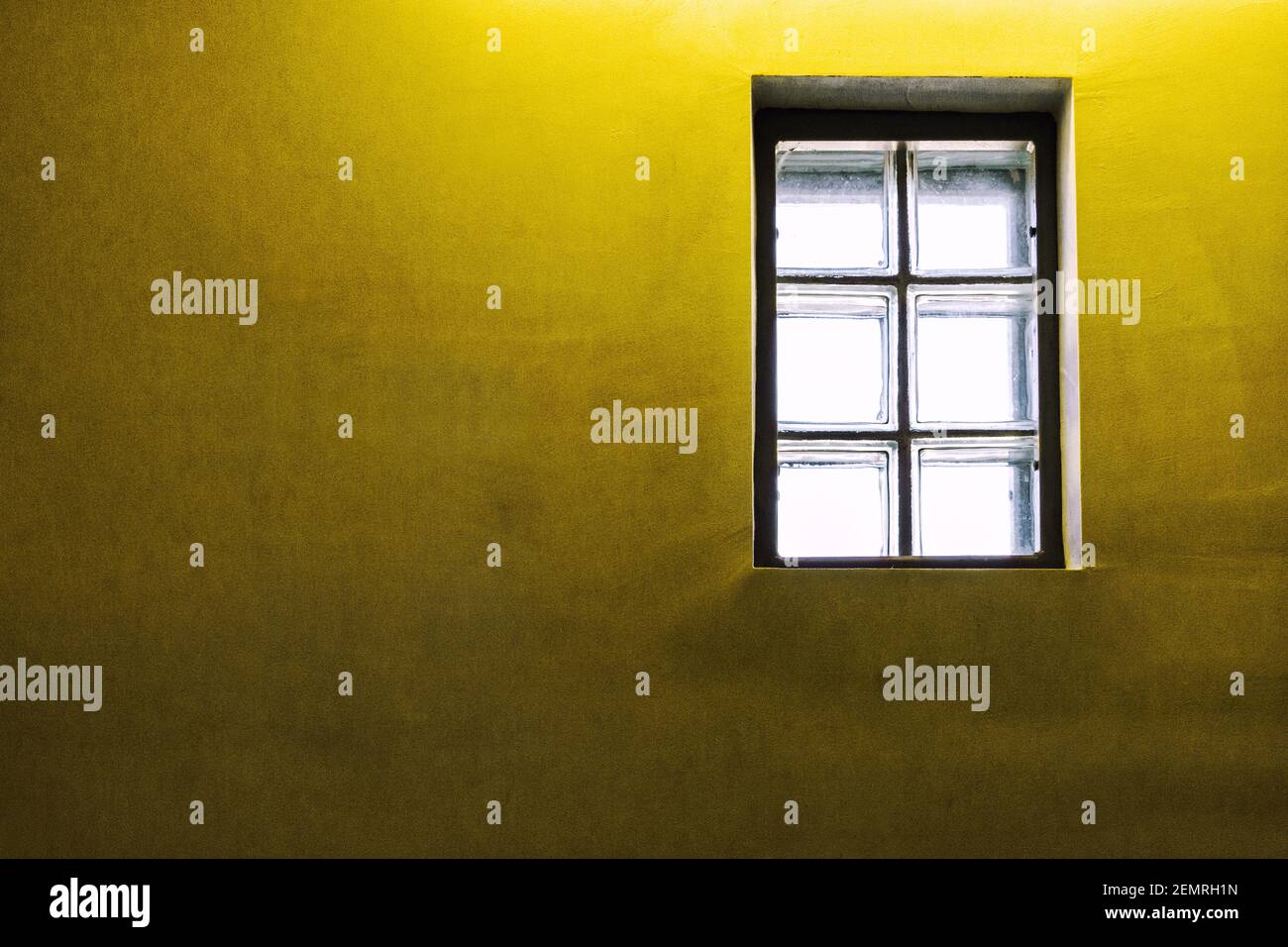 Ein Glasblockfenster in einem leeren Treppenhaus erzeugt ein helles Licht in den Farben 2021 PANTONE 13-0647 Illuminating und 17-5104 Ultimate Grey Stockfoto