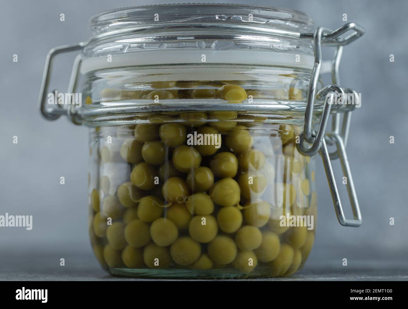 Nahaufnahme von eingelegten Oliven im Glas über grau Hintergrund Stockfoto