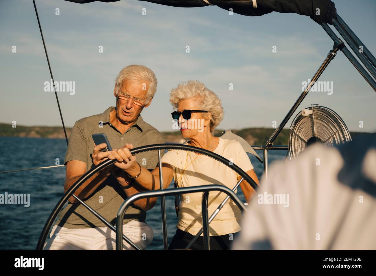 Ältere Paare, die während der Fahrt mit dem Smartphone in Richtung navigieren Boot an sonnigen Tagen Stockfoto