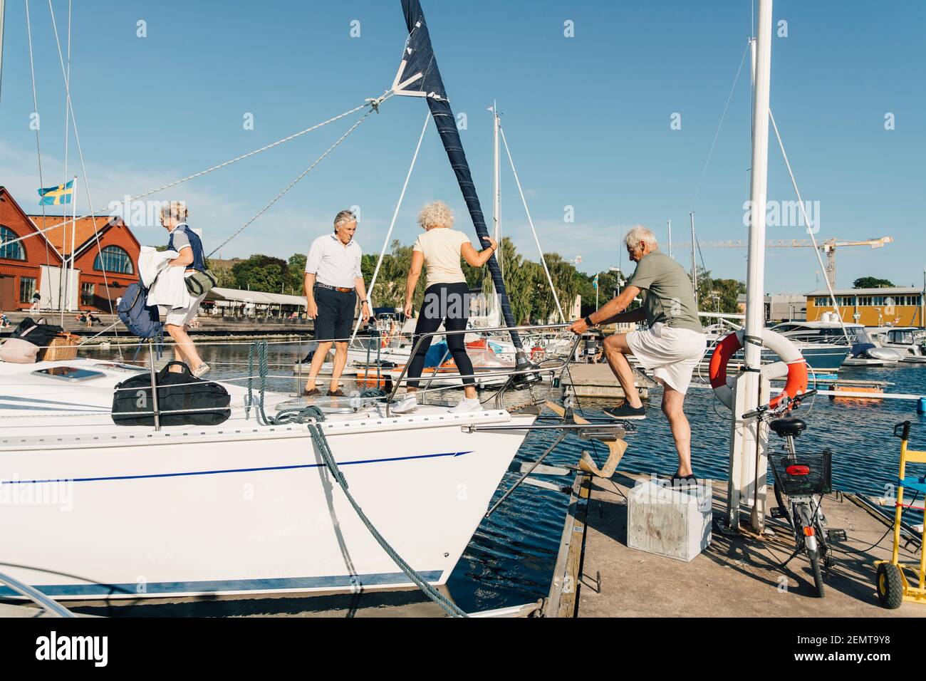 Aktive ältere Paare, die an sonnigen Tagen im Hafen ein Boot besteigen Stockfoto