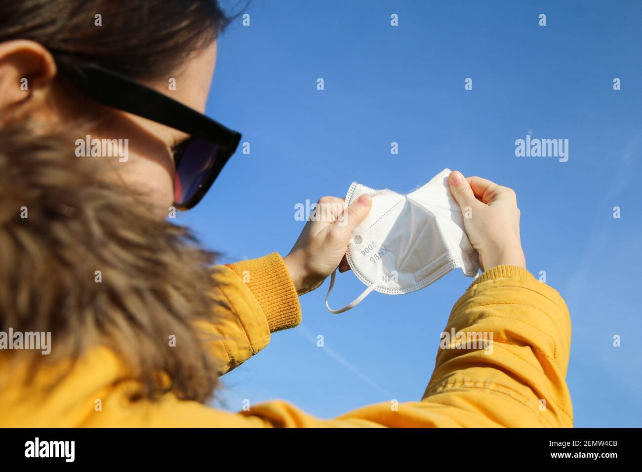 Die Frau zerreißt die Gesichtsmaske des Atemschutzgeräts FFP2, die zum Schutz vor dem Corona-Virus verwendet wird. Symbol für Freiheit nach Ende der Pandemie. Stockfoto