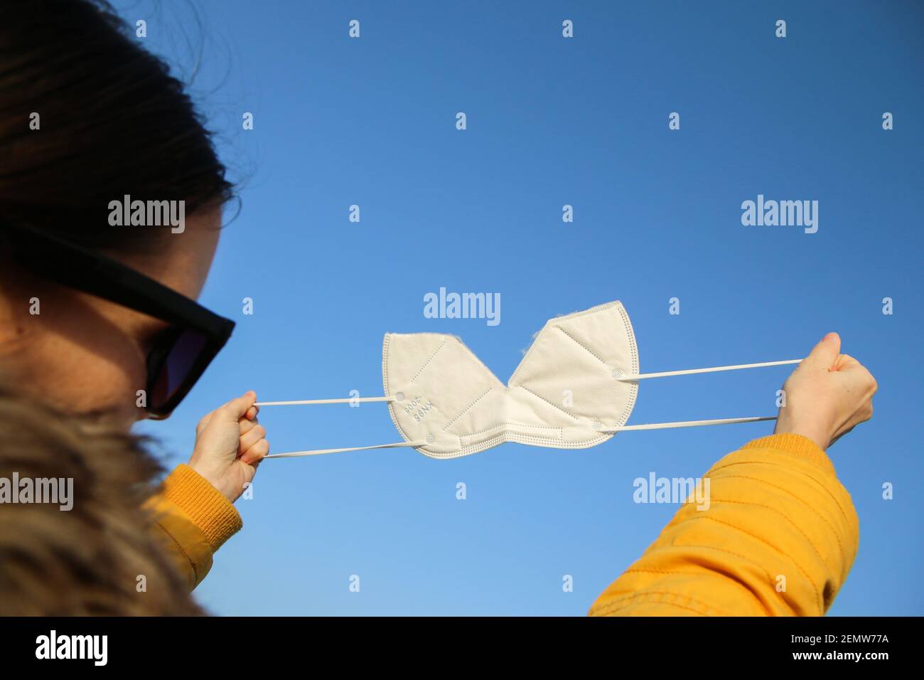 Die Frau zerreißt die Gesichtsmaske des Atemschutzgeräts FFP2, die zum Schutz vor dem Corona-Virus verwendet wird. Symbol für Freiheit nach Ende der Pandemie. Stockfoto