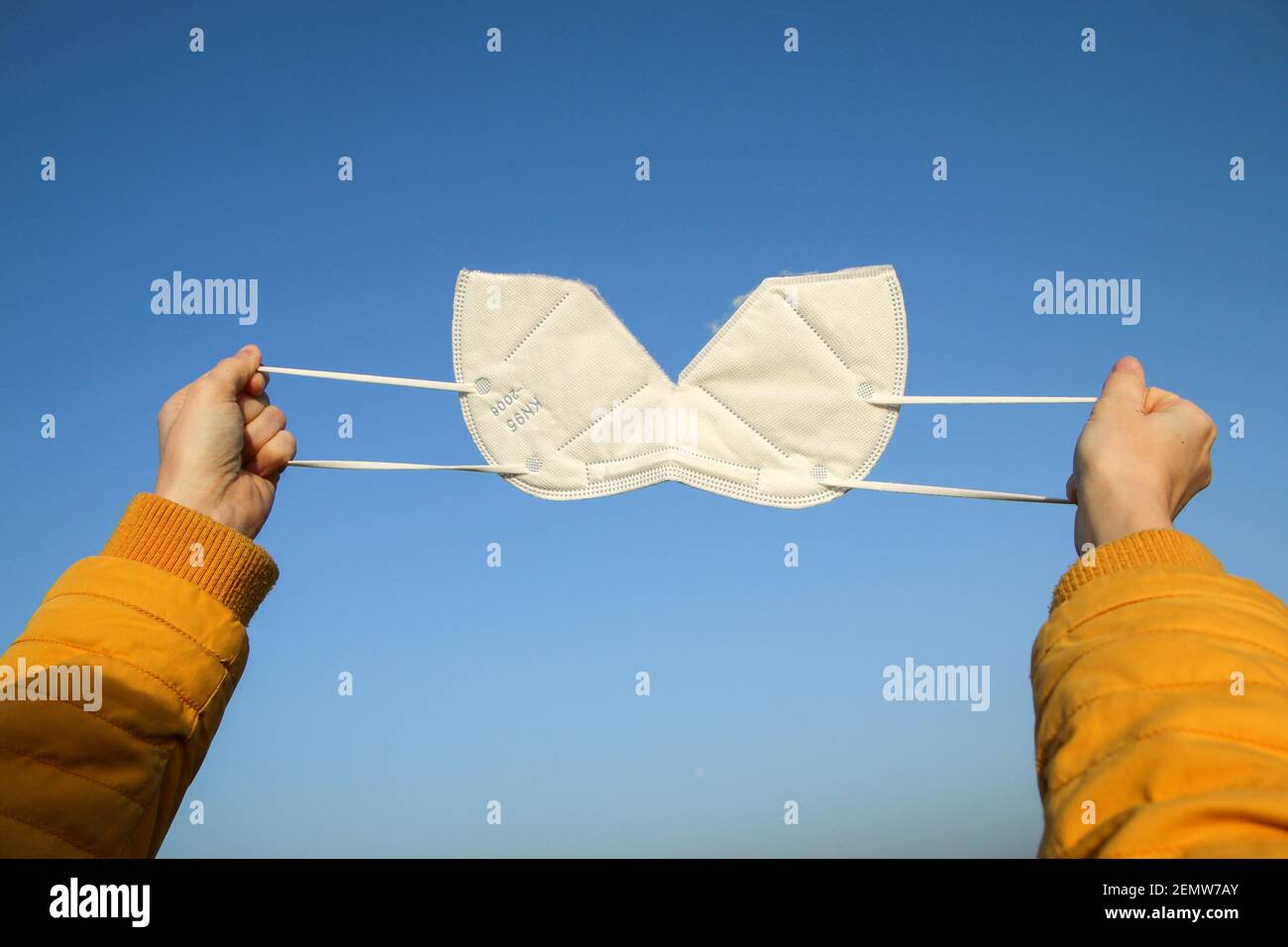 Die Frau zerreißt die Gesichtsmaske des Atemschutzgeräts FFP2, die zum Schutz vor dem Corona-Virus verwendet wird. Symbol für Freiheit nach Ende der Pandemie. Stockfoto
