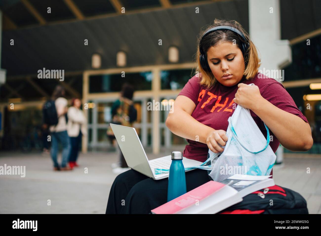 Weibliche College-Studentin guckt in Tasche, während sie in der Universität sitzt Stockfoto
