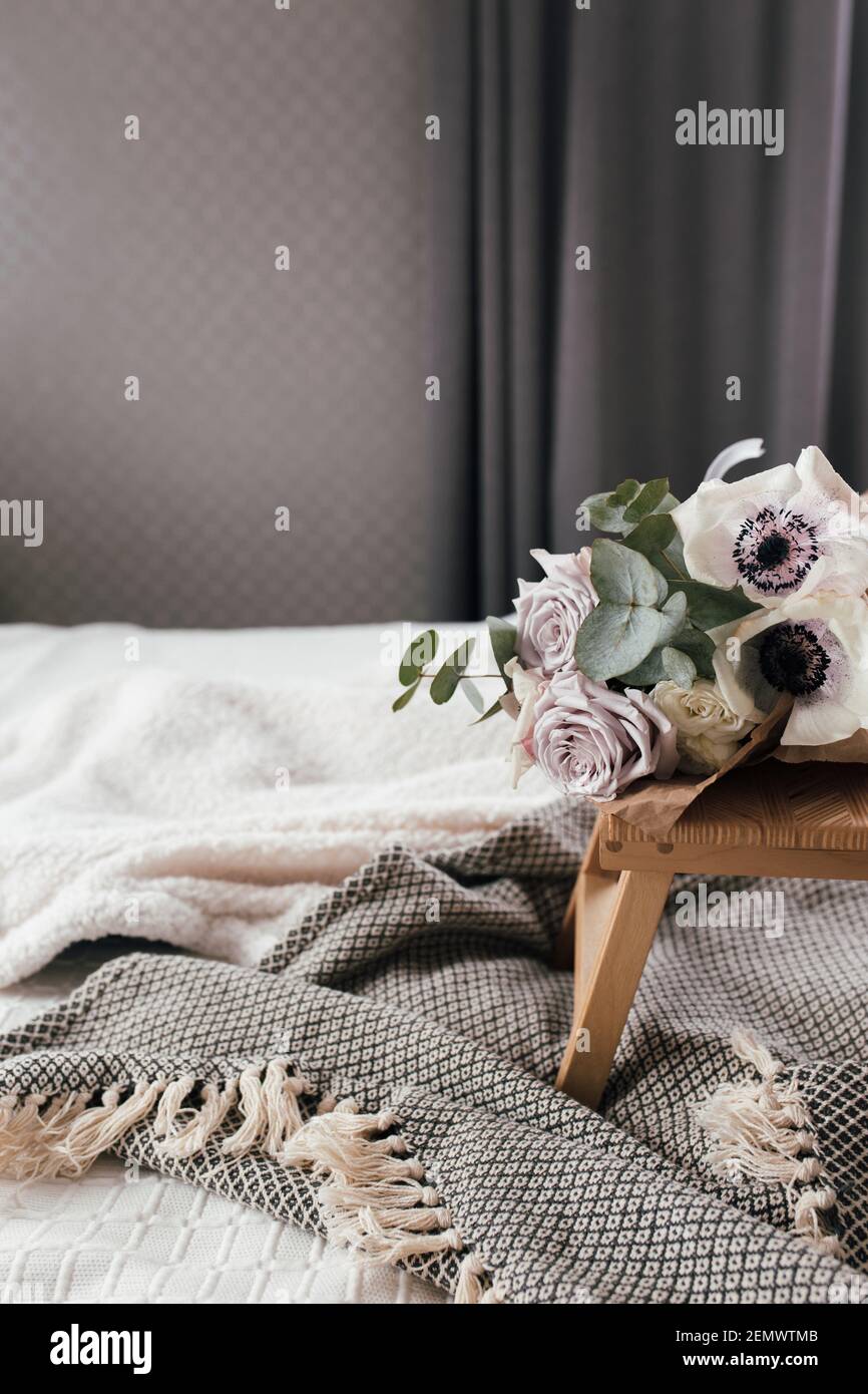 Romantischer Morgen. Couchtisch aus Holz mit Blumen auf dem Bett und Decke. Fliederrosen mit Eukalyptus und Anemonen. Grautöne im Innenbereich. Hoher pH-Wert Stockfoto