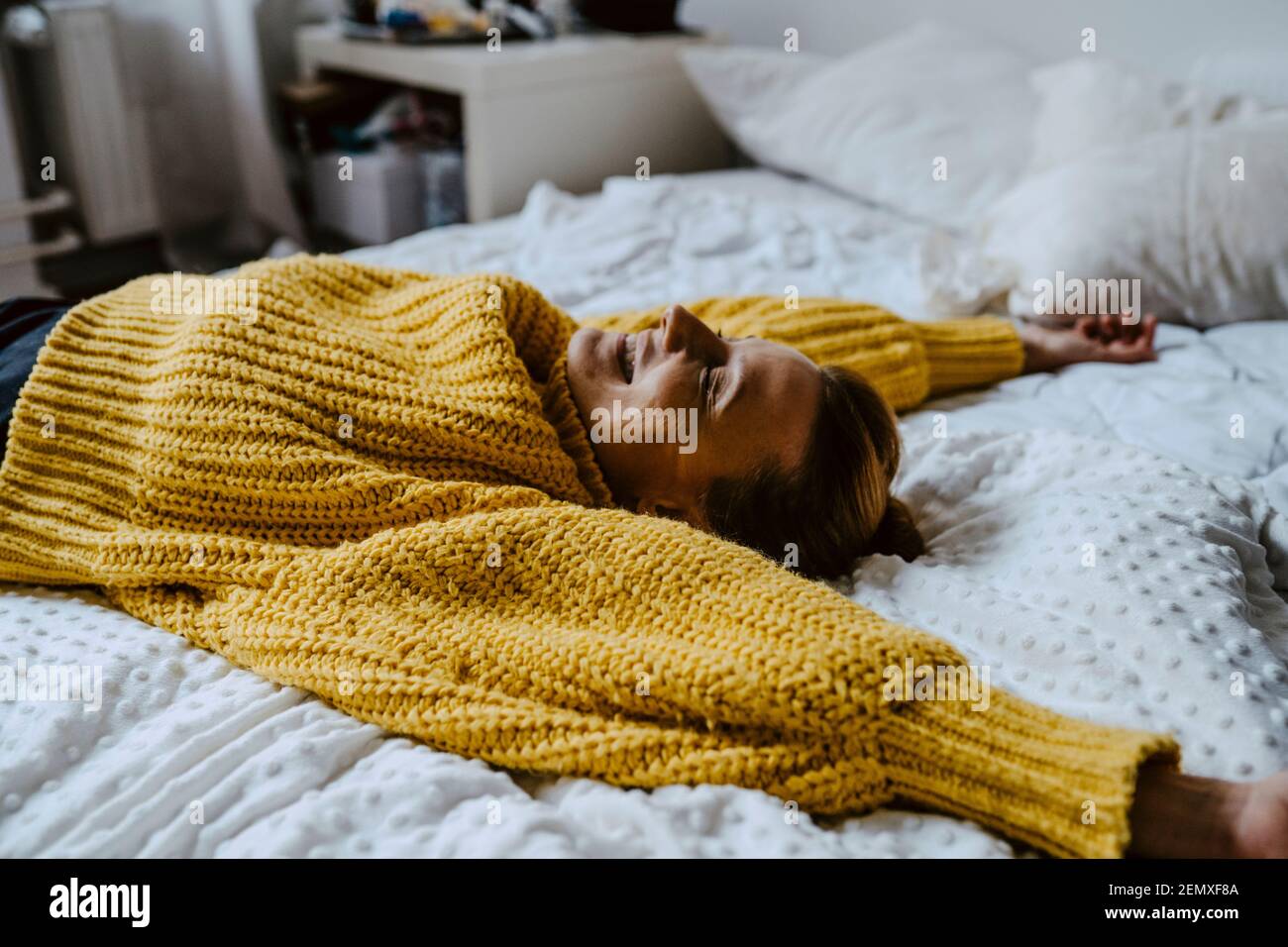 Frau mit erhobener Hand, die zu Hause auf dem Bett liegt Stockfoto