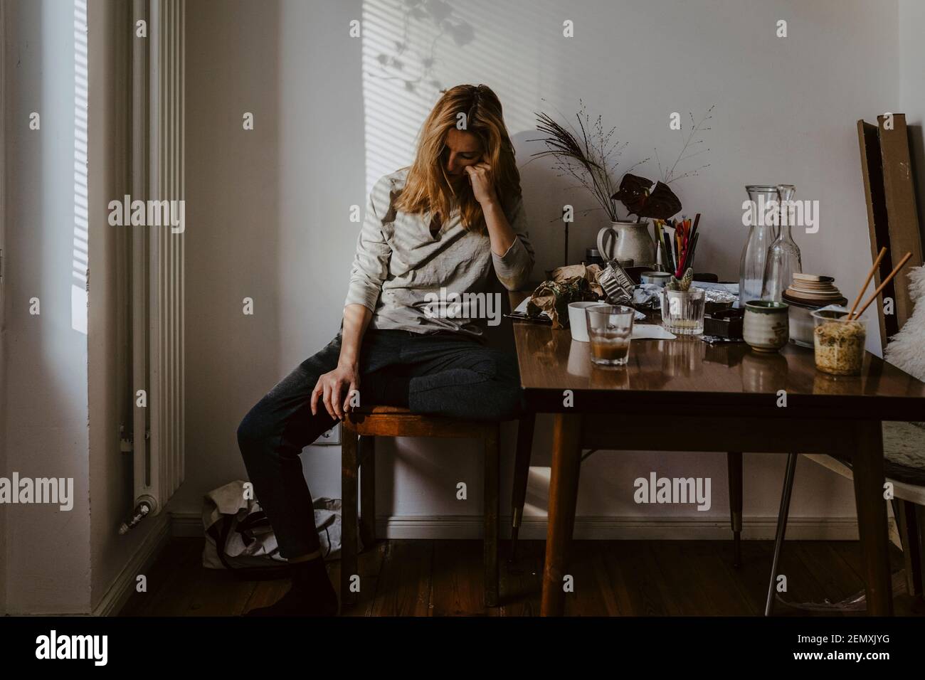 Deprimierte Frau sitzt auf einem Stuhl im Wohnzimmer Stockfoto