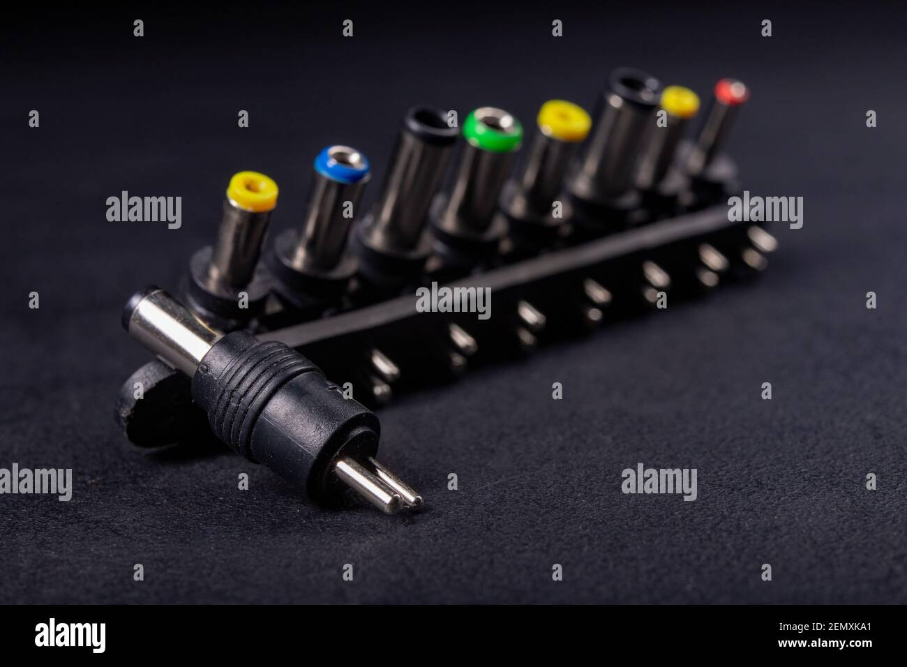 Netzteilanschlüsse für Laptops. Zubehör für die Stromversorgung elektronischer Geräte. Dunkler Hintergrund. Stockfoto