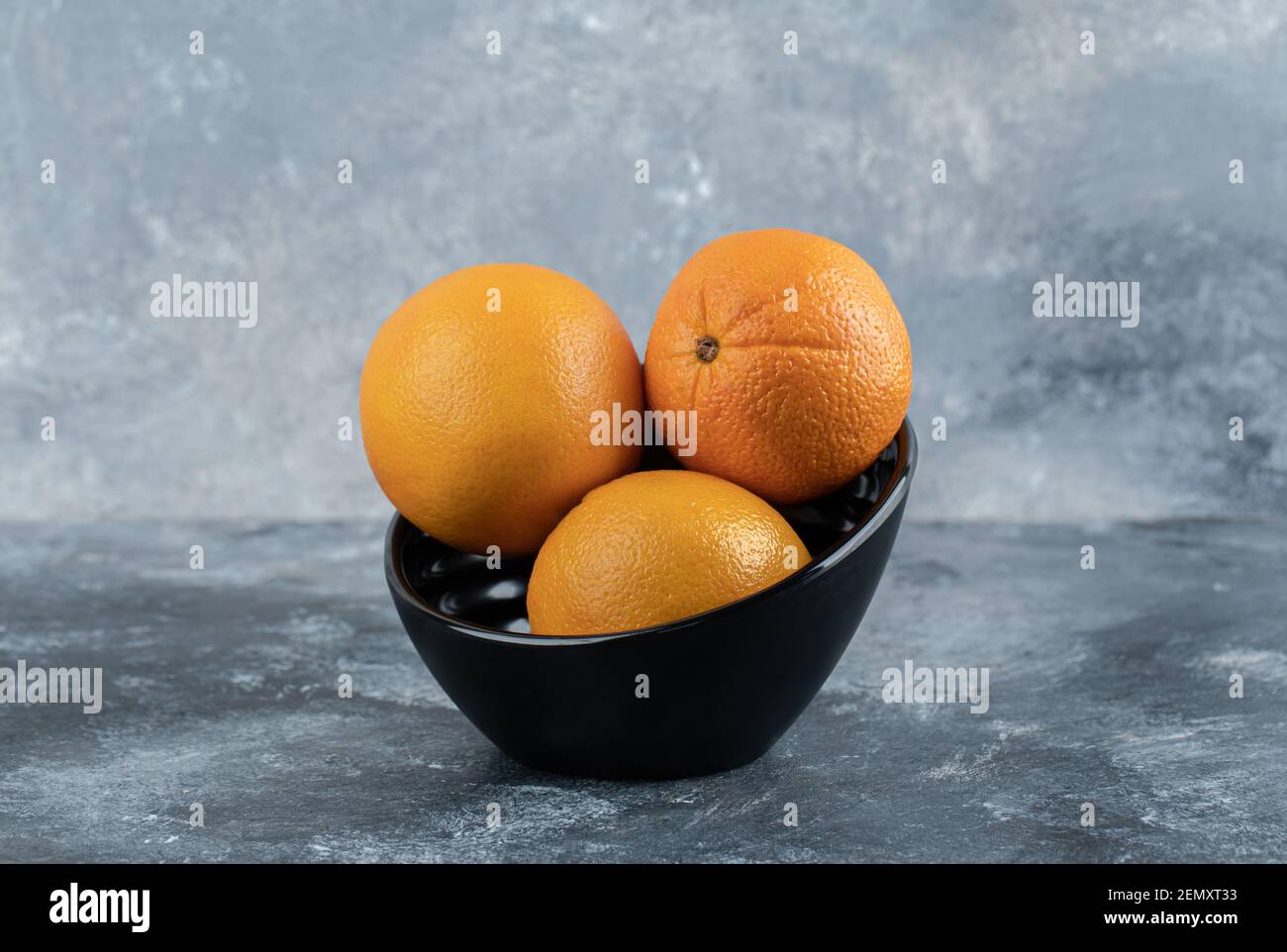 Drei frische Orangen in schwarzer Schale Stockfoto