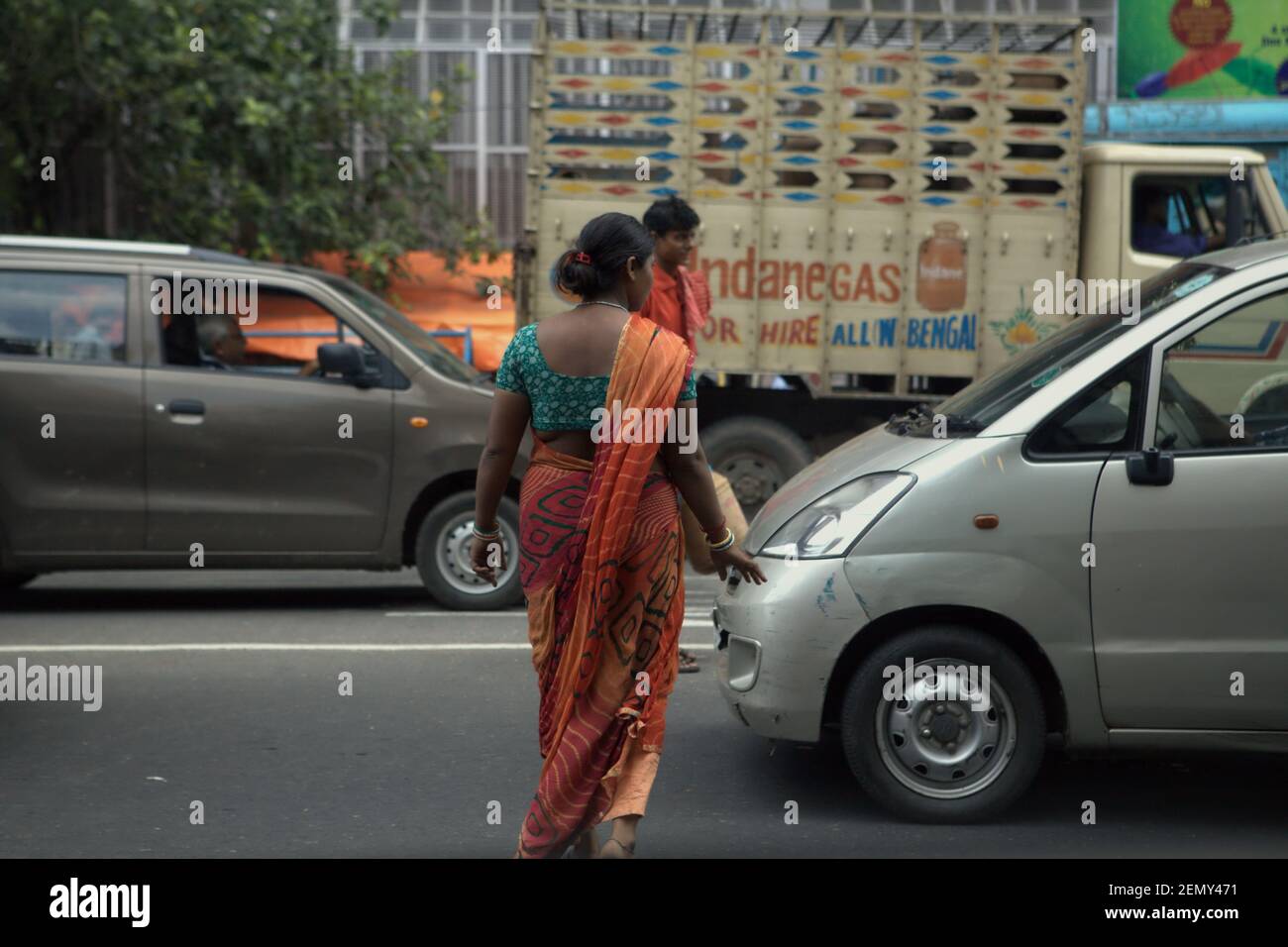 Eine Frau, die während eines Staus in Kalkutta, Westbengalen, Indien, eine Straße überquert. Stockfoto