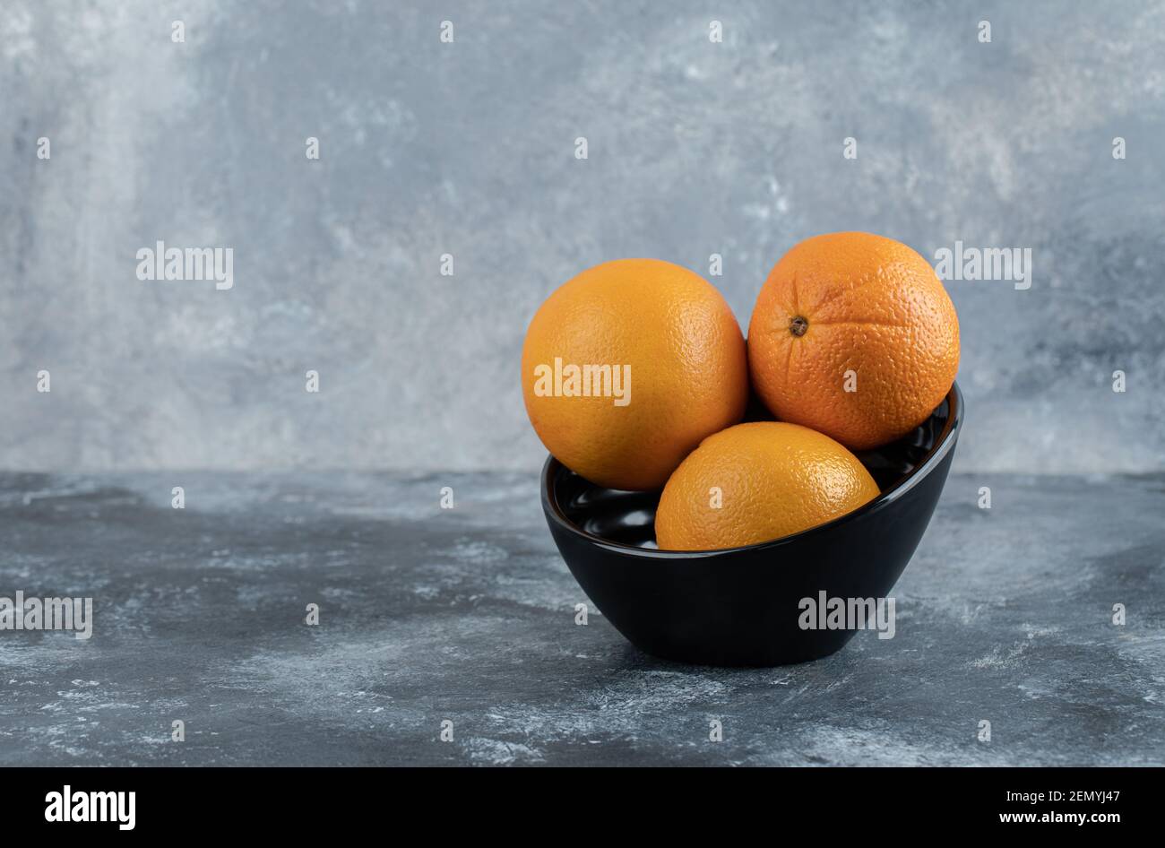 Drei frische Orangen in schwarzer Schale Stockfoto