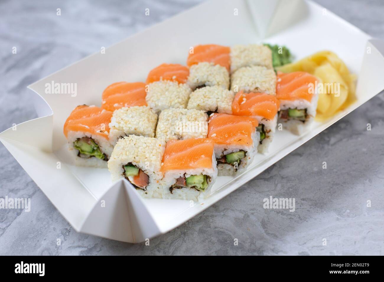 Takeaway-Box mit Sushi-Rollen auf Steintisch. Sushi-to-go-Konzept. Stockfoto