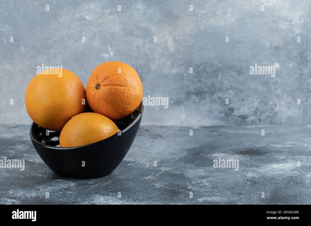 Drei frische Orangen in schwarzer Schale Stockfoto
