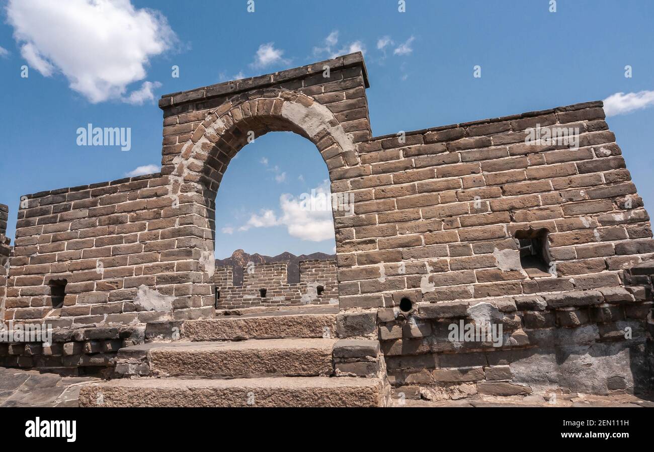 Peking, China - 28. April 2010: Große Mauer in China. Braune Steinmauer mit Bogen als Eingang zur Aussichtsplattform unter blauer Wolkenlandschaft. Stockfoto