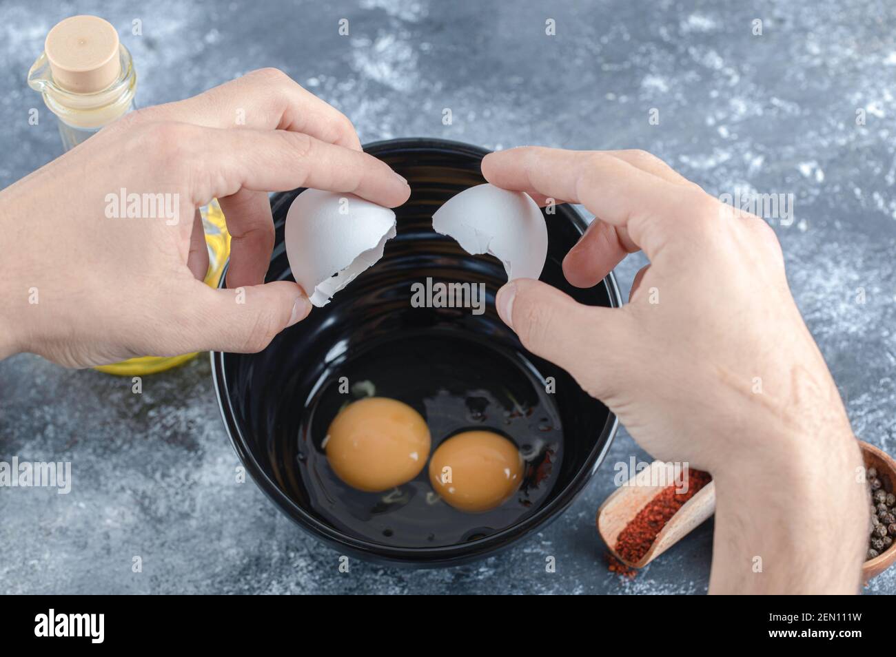 Männliche Hände brechen Eier . Öl und Gewürze Stockfoto
