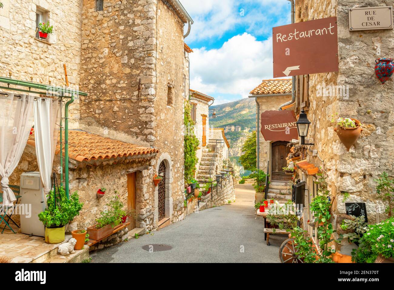 Eine schmale Gasse von Cafés und Geschäften in der Hügel gemauerten mittelalterlichen Dorf Gourdon, Frankreich. Stockfoto