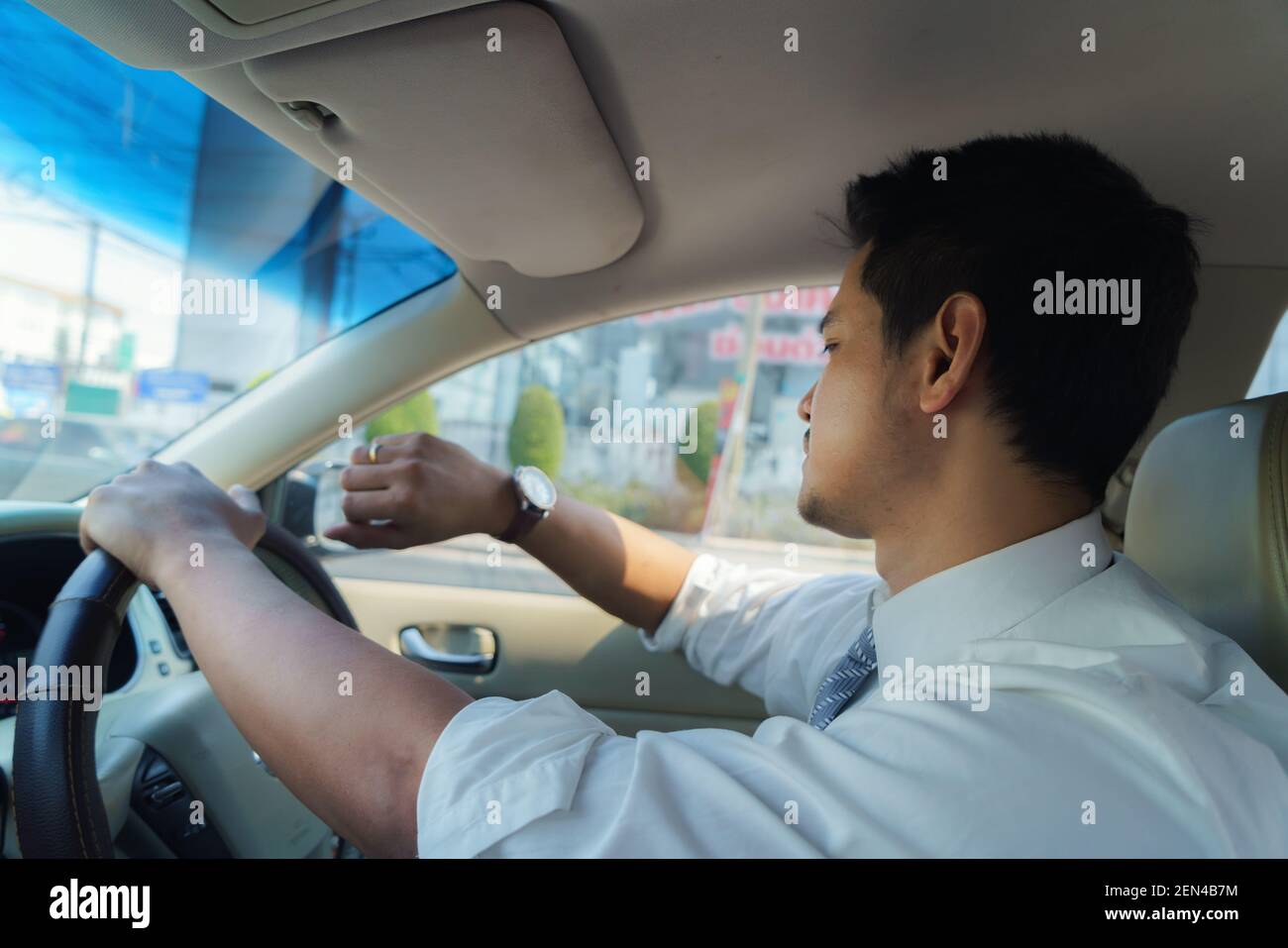 Asiatischer Mann sieht seine Uhr, wie er morgens zur Arbeit fährt, spät zur Arbeit. Verkehrsstaus Stockfoto