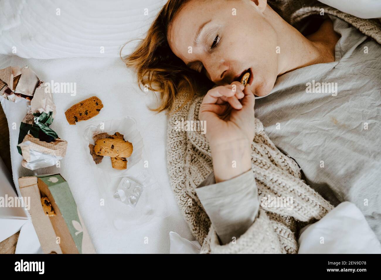 Aus der Sicht der Frau, die beim Liegen Kekse isst Bett zu Hause Stockfoto