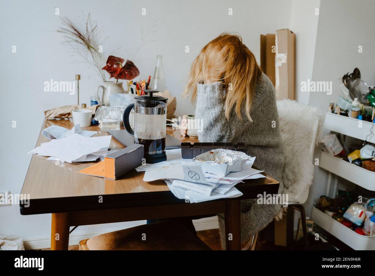 Geschäftsfrau mit geistiger Störung sitzt auf Stuhl im Wohnzimmer Stockfoto